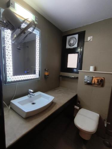 a bathroom with a sink and a toilet and a mirror at The Hermitage by The Cosy Hotels Near Lotus Temple in New Delhi