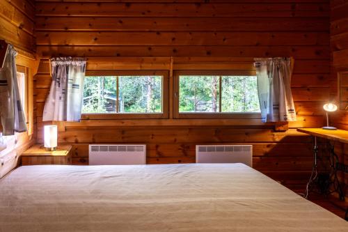 a bedroom with a large bed and two windows at Mökki Kalliola in Puumala