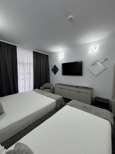 ein Hotelzimmer mit zwei Betten und einem Flachbildfernseher in der Unterkunft Hotel Daly in Ploieşti