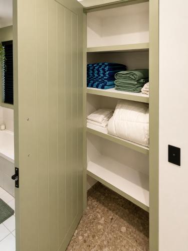 a walk in closet with white shelves and towels at Peaceful tropical retreat with pool, mineral spa & Games room in Gold Coast