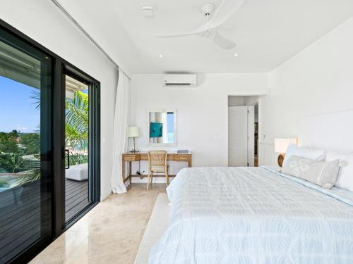 a white bedroom with a large bed and a desk at La Sirène in Simpson Bay