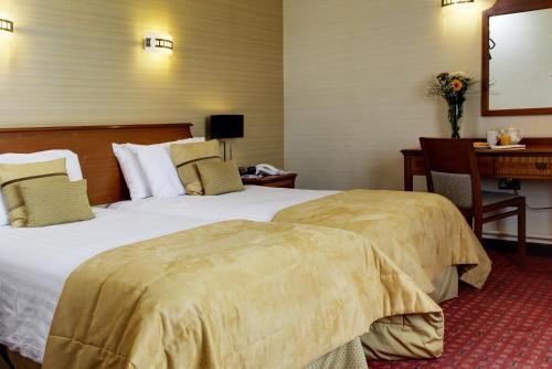 a hotel room with two beds and a desk at Best Western Aberavon Beach Hotel in Port Talbot