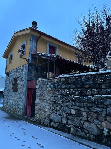 a stone building with a stone wall next to a street at Legendarium Casa Rural in Salamón