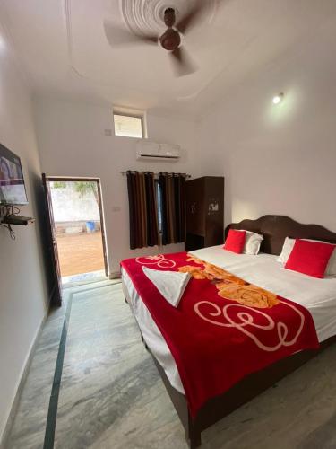 a bedroom with a large bed with a red blanket at Good Karma B&B in Khajurāho