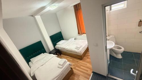 a small bathroom with two beds and a toilet at METRO Hotel in Gusinje