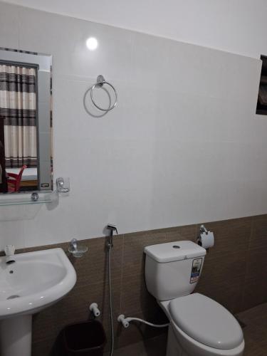 a bathroom with a white toilet and a sink at Beach Life Long Beach Resort in Trincomalee