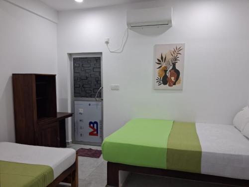 a room with two beds and a television in it at Beach Life Long Beach Resort in Trincomalee