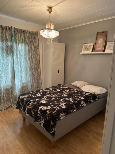 a bedroom with a bed and a chandelier at Wooden House 2 bedrooms in Turku