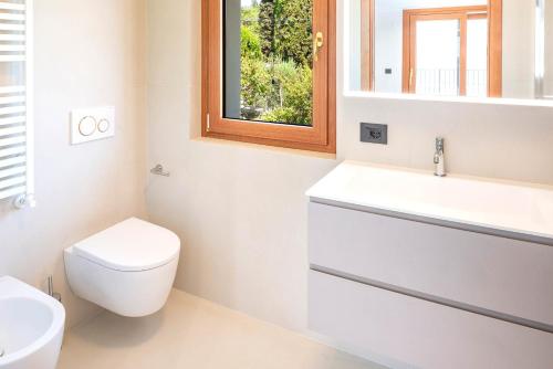 a bathroom with a toilet and a sink and a window at Villa Sonia in Bardolino