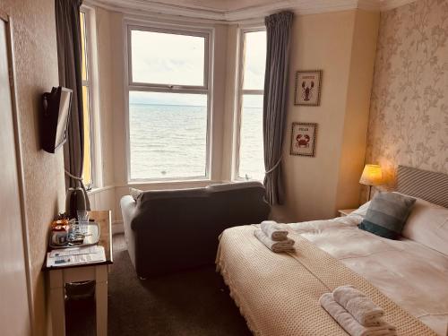 a bedroom with a bed and a window with the ocean at Awel Mor in Criccieth