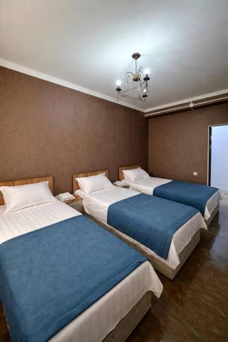 a room with three beds with blue sheets at Kut Hotel in Karakol