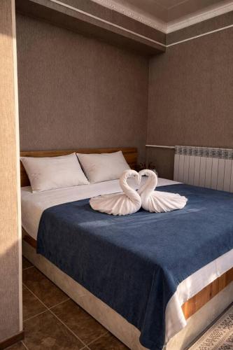 two swans shaped like hearts sitting on a bed at Kut Hotel in Karakol