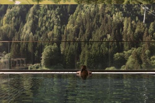 a woman in a swimming pool with a view of a mountain at Hotel Marten -Joker Card Partner- in Saalbach-Hinterglemm