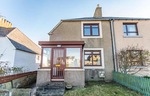 a house with a red door in front of it at Beach House in Thurso