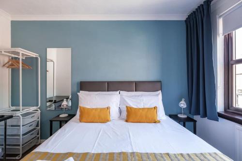 a blue bedroom with a bed with two orange pillows at The Douglas - Spacious 2 bed apartment in Uddingston in Uddingston
