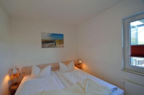 a bedroom with a bed with white sheets and pillows at Bella Casa 34 - Strandblick in Juliusruh