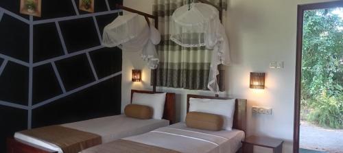a bedroom with two beds and a window and lights at Peacock Lake Villa in Habarana
