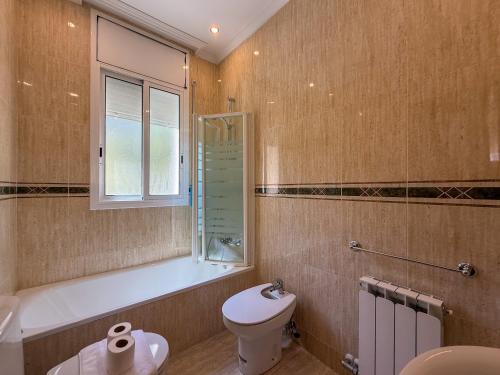 a bathroom with a toilet and a tub and a sink at Villa Claudia by Hello Homes Sitges in Sitges