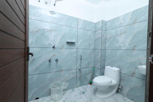 a bathroom with a toilet and a wall of tiles at Bright Nest Service Villa Munroe in Kollam
