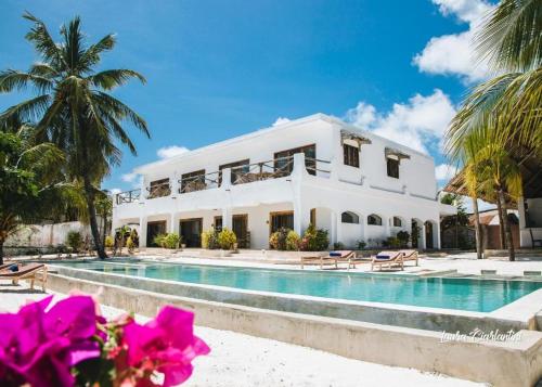 ein weißes Haus mit Swimmingpool und Palmen in der Unterkunft Moonshine Uroa Boutique Hotel in Uroa