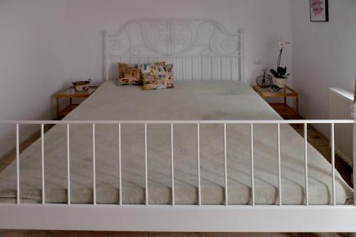 a bedroom with a white bed with a white railing at Pensiunea Grădina Ascunsa in Bughea de Jos