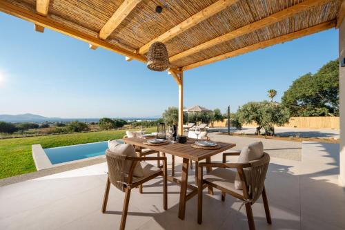 an outdoor dining room with a wooden table and chairs at Ampeli Residences-Sea view-Private Pool in Zipárion
