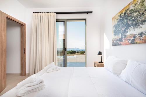 a white bedroom with a large white bed and a window at Ampeli Residences-Sea view-Private Pool in Zipárion