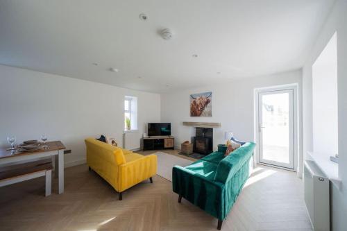 a living room with a green couch and yellow chairs at Easter Cottage -4 Bed Converted Barn Cottage in Turriff