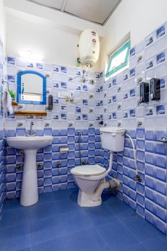 a blue tiled bathroom with a toilet and a sink at The Hood Bir Billing in Bīr
