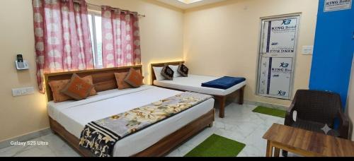 a bedroom with two beds and a table and a window at Hotel Shree Rameshwaram Near by All Temple in Ayodhya
