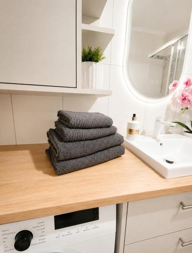 a pile of towels sitting on a counter next to a sink at Kaszmirowy Apartament in Wałcz