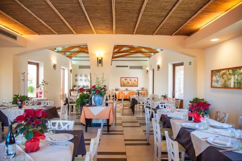une salle à manger avec des tables et des chaises blanches et des fleurs rouges dans l'établissement Alle Querce Hotel Ristorante, à Castelbuono