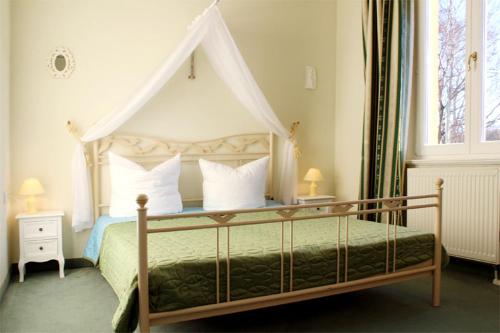 ein Schlafzimmer mit einem Himmelbett und weißen Kissen in der Unterkunft Appartmenthaus Sonnenresidenz I in Kühlungsborn