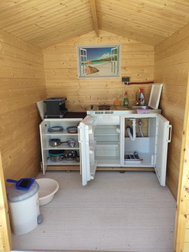a small kitchen in a wooden cabin with a sink at Caravan with private toilet and kitchen 2 in Grebaštica