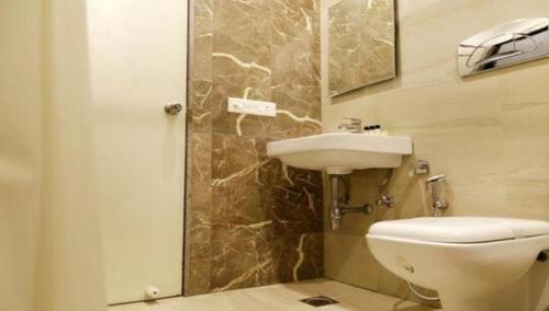a bathroom with a white toilet and a sink at Hotel Tanman Continental, Rajgir in Rājgīr Kund