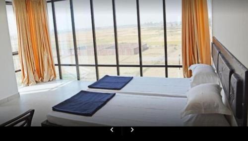 a bedroom with two beds and a large window at Hotel Tanman Continental, Rajgir in Rājgīr Kund