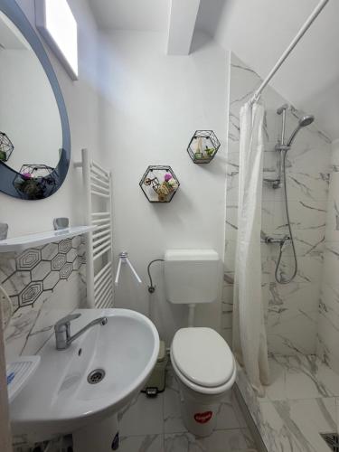 a white bathroom with a toilet and a sink at Vila MaeStar in Curtea de Argeş