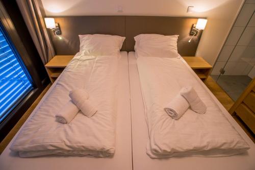 two beds in a room with two pairs of slippers at Appart Gastauer in Sankt Gallenkirch