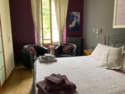 a bedroom with a bed and two chairs and a window at Casa Vacanza Pigna in Pigna