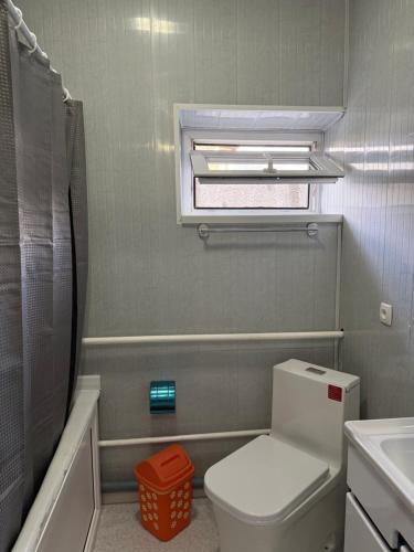 a bathroom with a toilet and a sink and a window at Yhome in Karakol