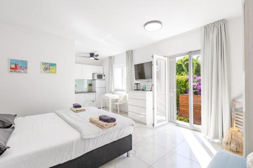 a white bedroom with a bed and a balcony at Apartments 2A in Petrcane