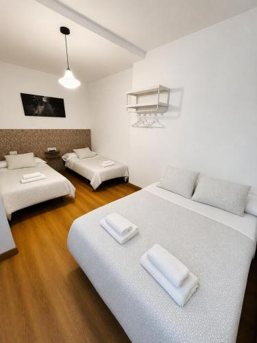 two beds in a room with white walls and wooden floors at Dos Romeiros in Palas de Rei