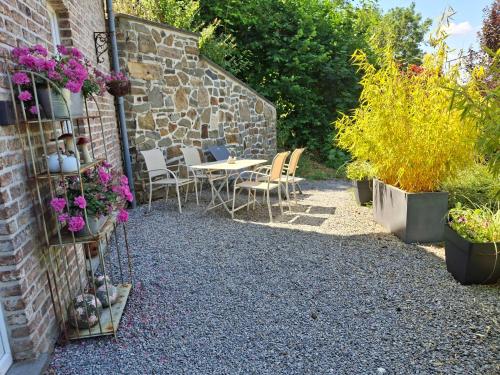 a patio with a table and chairs and flowers at La Maison des Senteurs in Francorchamps
