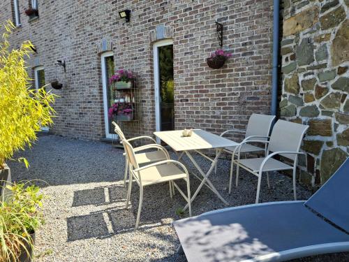a patio with a table and chairs next to a brick building at La Maison des Senteurs in Francorchamps