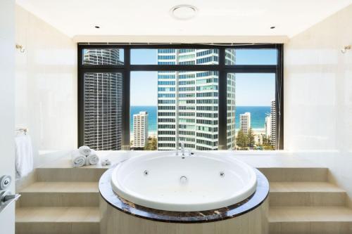 a bathroom with a tub and a large window at voco Gold Coast by IHG in Gold Coast
