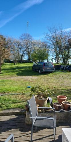 a chair sitting on a patio with a car in a field at Lejbølle gamle Bageri værelse 2 in Bøstrup
