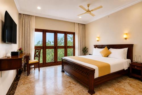 a bedroom with a large bed and a television at Astralis Resort Coorg in Madikeri