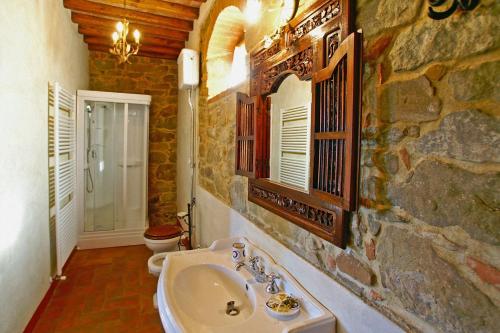 La salle de bains est pourvue d'un lavabo et d'un mur en pierre. dans l'établissement Villa Ceppeto, à Monte San Savino