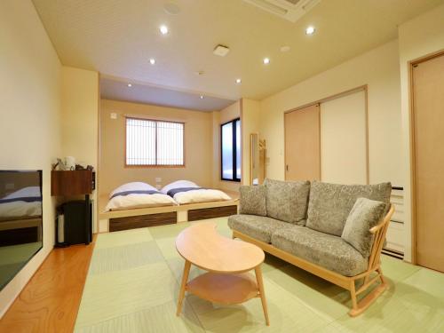 a living room with a couch and a table and a bed at Dogo Onsen Yachiyo 道後温泉八千代 in Matsuyama