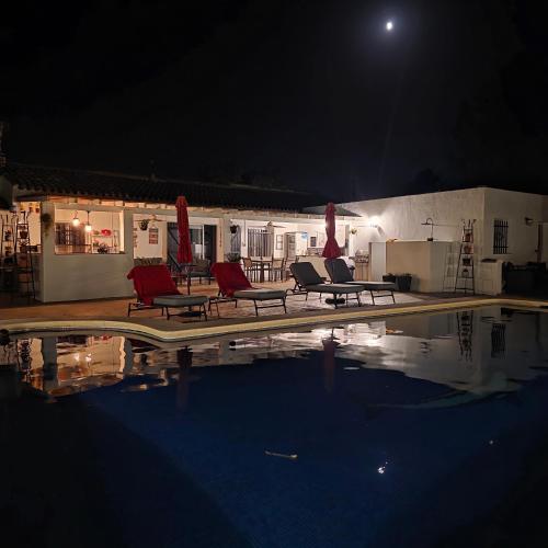 a swimming pool at night with red chairs next to a house at Casa de las Murallas, Bed&Breakfast in Yecla